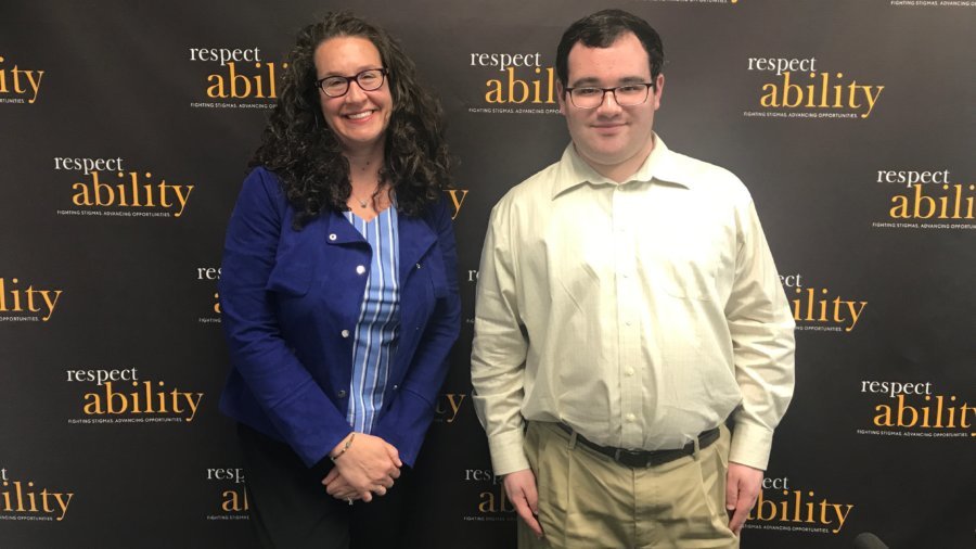 RespectAbility Board Member Dana Marlowe and RespectAbility Fellow Eric Ascher smiling in front of the RespectAbility banner