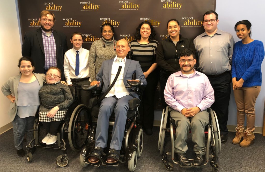 Lenny Larsen with RespectAbility staff and Fellows in front of the RespectAbility banner