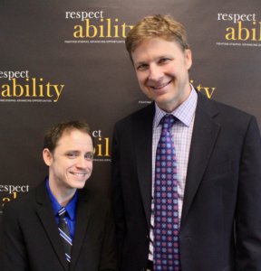 Derek Shields and RespectAbility Fellow Ryan Knight smiling in front of the RespectAbility banner