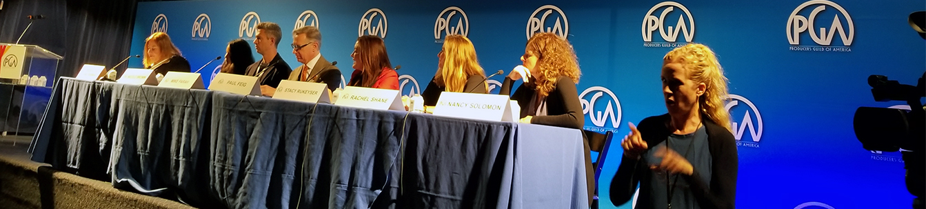 Members of the inclusion panel seated behind a table while an ASL interpreter is in lower right corner