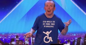 Lee Ridley wearing shirt saying "I'm only in it for the parking" against blue backgroun