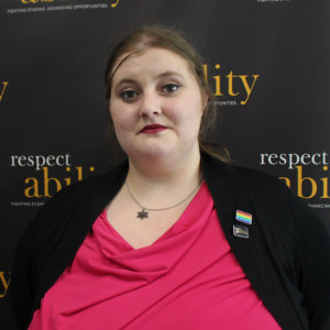 Headshot of Lily in professional dress in front of RespectAbility banner