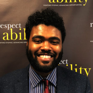 Zavier Taylor in professional dress in front of respectability sign
