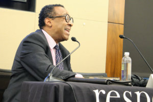 Clarence Page speaking into a microphone at RespectAbility's intersectionality panel
