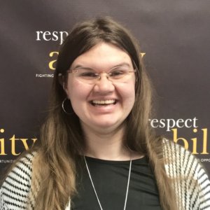 Heidi Wangelin smiling in front of the RespectAbility banner