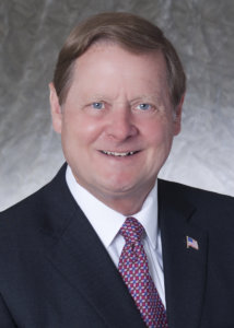 Steve Bartlett headshot in black suit, white shirt, red tie