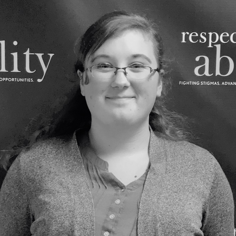 Emma Content smiling in front of the RespectAbility banner