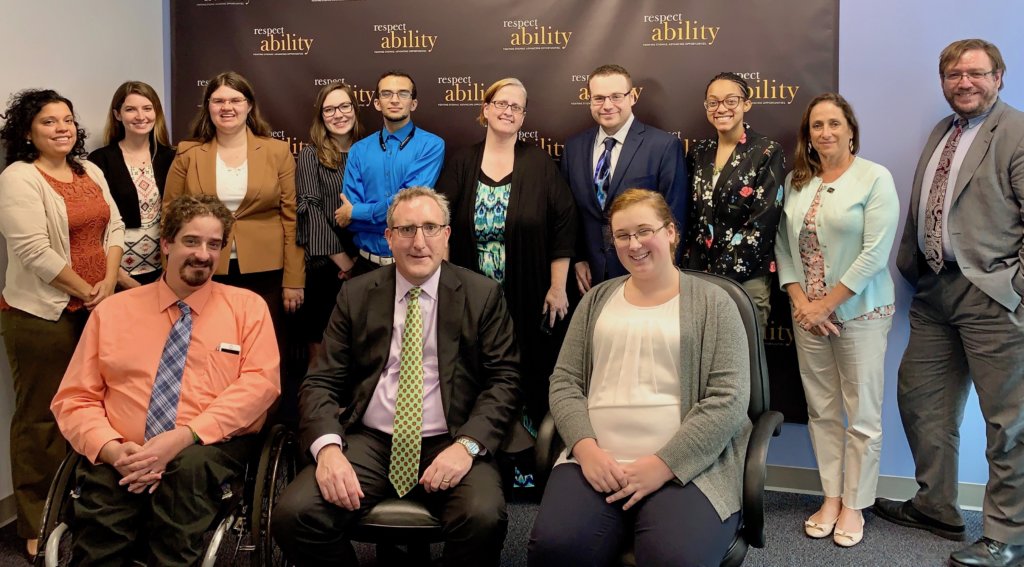 Andy Imparato with RespectAbility staff and Fellows in front of the RespectAbility banner