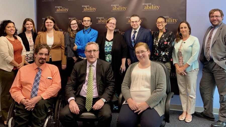 Andy Imparato with RespectAbility staff and Fellows in front of the RespectAbility banner