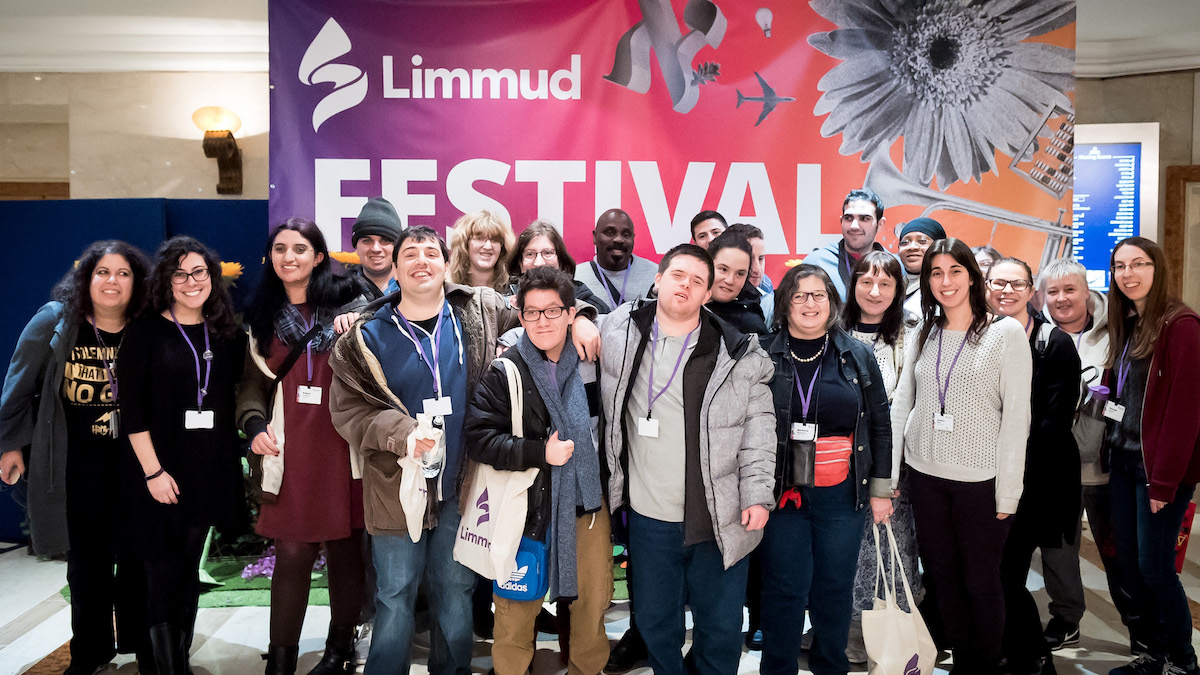 Members of the Limmud La’am Program with some Limmud Inclusion volunteers last year at Limmud Festival smiling together in front of a banner