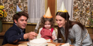Zac Efron, Macie Carmosino, and Lily Collins sitting in front of a birthday cake.