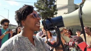 A woman talking into a megaphone as several people look on behind her