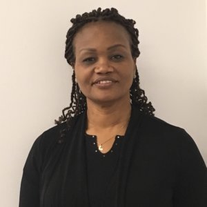 Dr. Nelle Richardson smiling in front of an undecorated white wall