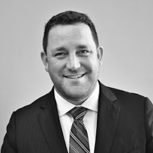 Aaron Dorfman smiling in a suit and tie