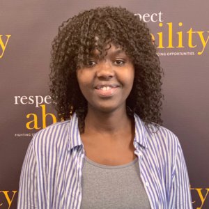 Angelique Uwabera smiling in front of the RespectAbility banner