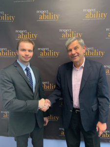 David Belkin and Jeremy Cooper shake hands in front of the RespectAbility banner