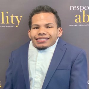 Justin Tapp smiling in front of the RespectAbility banner