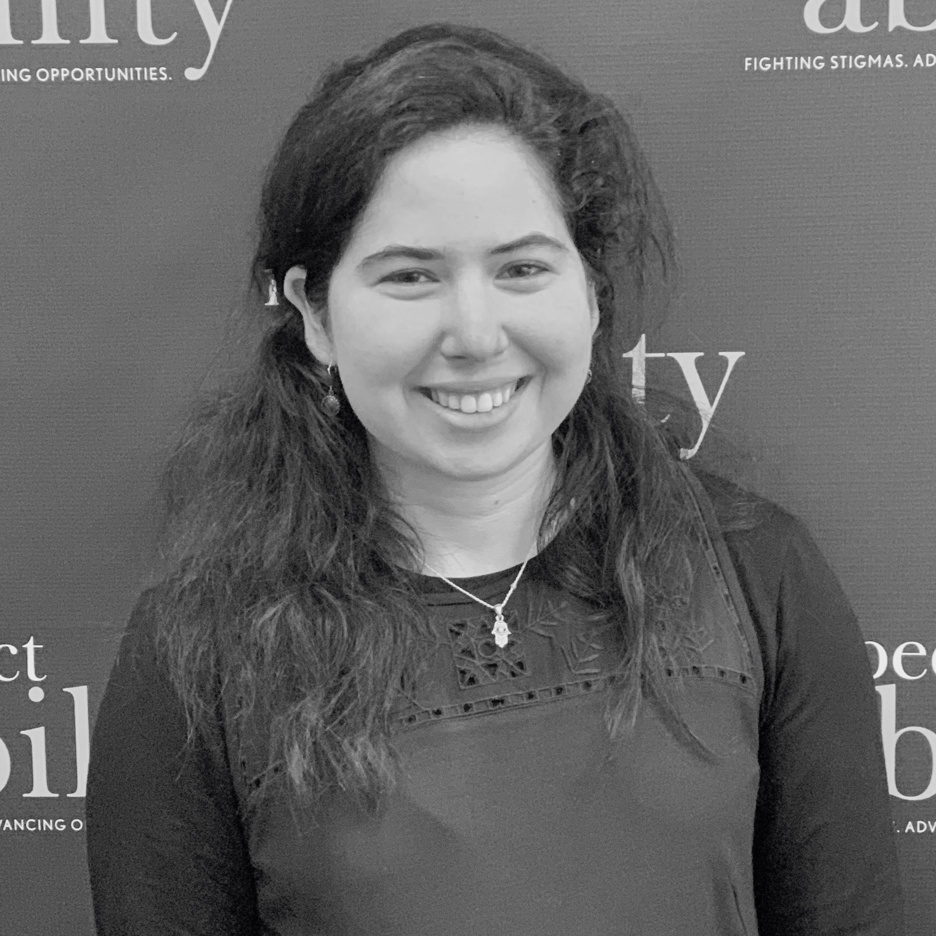 Madeleine Tasini smiling in front of the RespectAbility banner