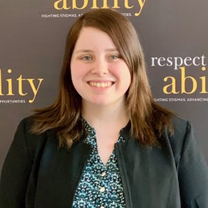 Megghan Duffy smiling in front of the RespectAbility banner