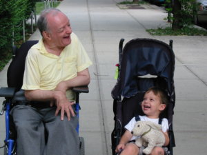Guila Franklin Siegel's dad and her son laughing. Her dad is in a wheelchair and her son is in a stroller