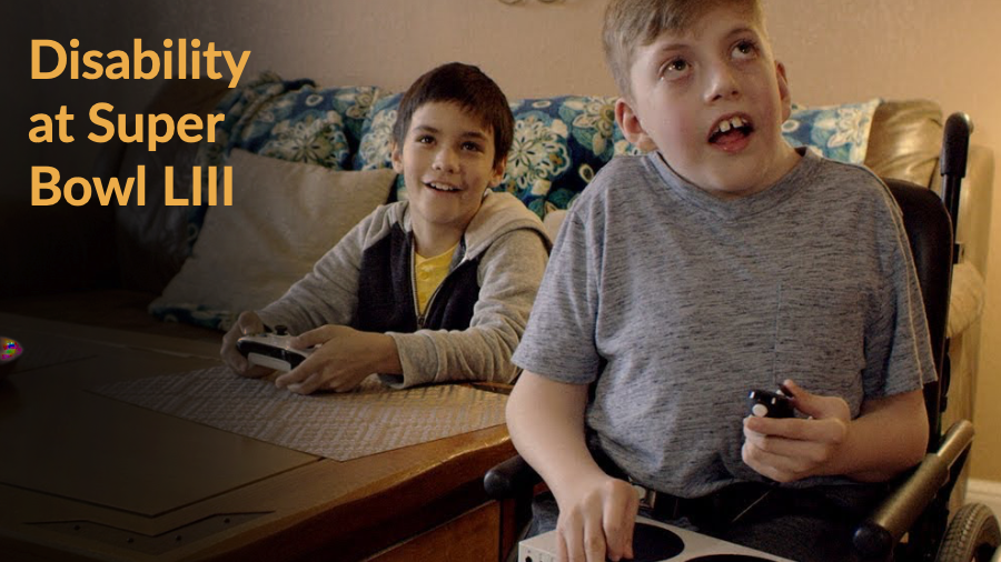 Still from Microsoft Commercial with two young boys playing video games, one of whom is a wheelchair user and playing with their adaptive controller. Text: Disability at Super Bowl LIII