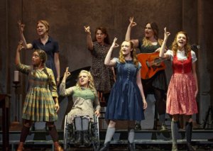 The cast of Spring Awakening with their right hands up on stage as part of a musical number