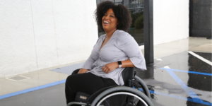 Tatiana Lee smiling in a parking lot. Tatiana is a wheelchair user.