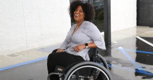 Tatiana Lee smiling in a parking lot. Tatiana is a wheelchair user.