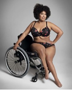 Tatiana Lee in lingerie holding onto her wheelchair behind her.