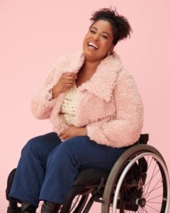 Tatiana Lee in a wheelchair wearing a pink jacket smiling