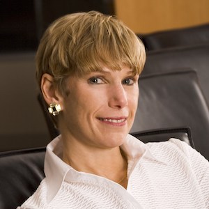 Lori Golden smiling sitting on a leather chair