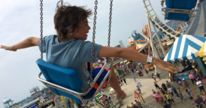 A still from Moonlight Sonata: Deafness in Three Movements with a young boy on an amusement park ride with his arms extended. Courtesy of Sundance Institute/photo by Irene Taylor Brodsky