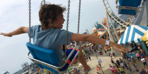 A still from Moonlight Sonata: Deafness in Three Movements with a young boy on an amusement park ride with his arms extended. Courtesy of Sundance Institute/photo by Irene Taylor Brodsky