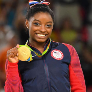 Simone Biles holding her gold medal at the Olympics