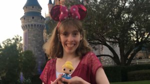 Emily Kranking with Minnie Mouse ears in front of Cinderella Castle holding a toy doll