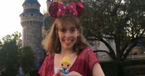 Emily Kranking with Minnie Mouse ears in front of Cinderella Castle holding a toy doll