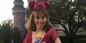 Emily Kranking with Minnie Mouse ears in front of Cinderella Castle holding a toy doll