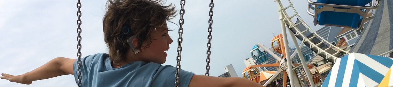 A still from Moonlight Sonata: Deafness in Three Movements with a young boy on an amusement park ride with his arms extended. Courtesy of Sundance Institute/photo by Irene Taylor Brodsky