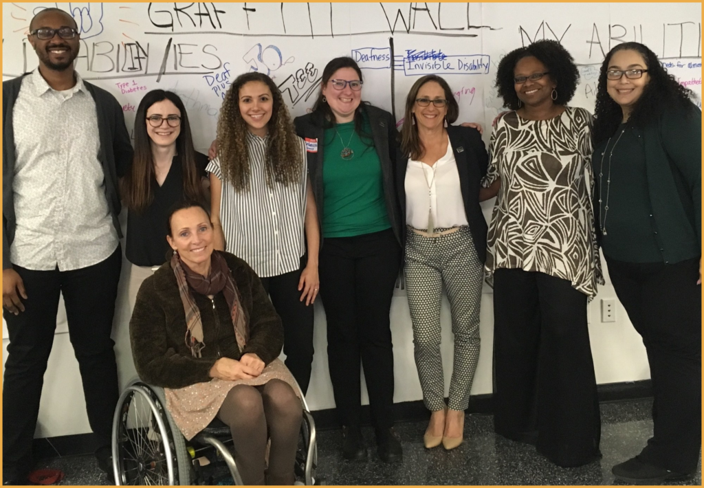 College Students event Panelists and facilitators smile together in front of the graffiti wall at the event