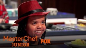 Ivy smiling on MasterChef Junior in the kitchen. Logos for MasterChef Junior and Fox