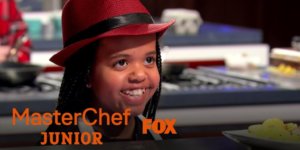 Ivy smiling on MasterChef Junior in the kitchen. Logos for MasterChef Junior and Fox