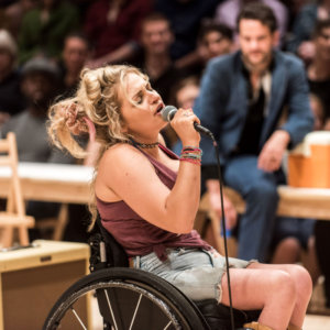 Ali Stroker singing into a microphone on stage for Oklahoma!