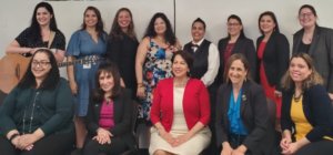 Presenters and facilitators at the Latinas with disabilities event smiling together in front of a white wall