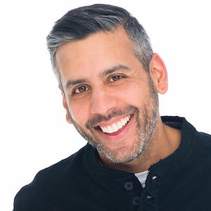 Karim Ahmad wearing a black polo shirt smiling in front of a white background