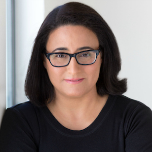 Sue Obeidi smiling wearing a black shirt in front of a white background