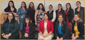 Presenters and facilitators at the Latinas with disabilities event smiling together in front of a white wall