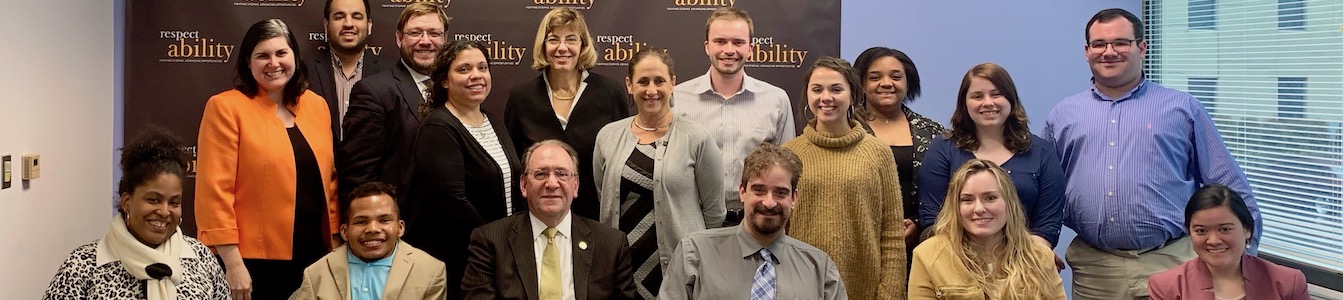 Neil Romano with RespectAbility staff and Fellows in front of the RespectAbility banner