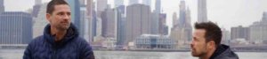 Warren Christie and Kurt Yaeger talking on The Village in front of the Hudson River with New York City's skyline in the background