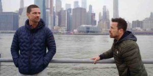 Warren Christie and Kurt Yaeger talking on The Village in front of the Hudson River with New York City's skyline in the background