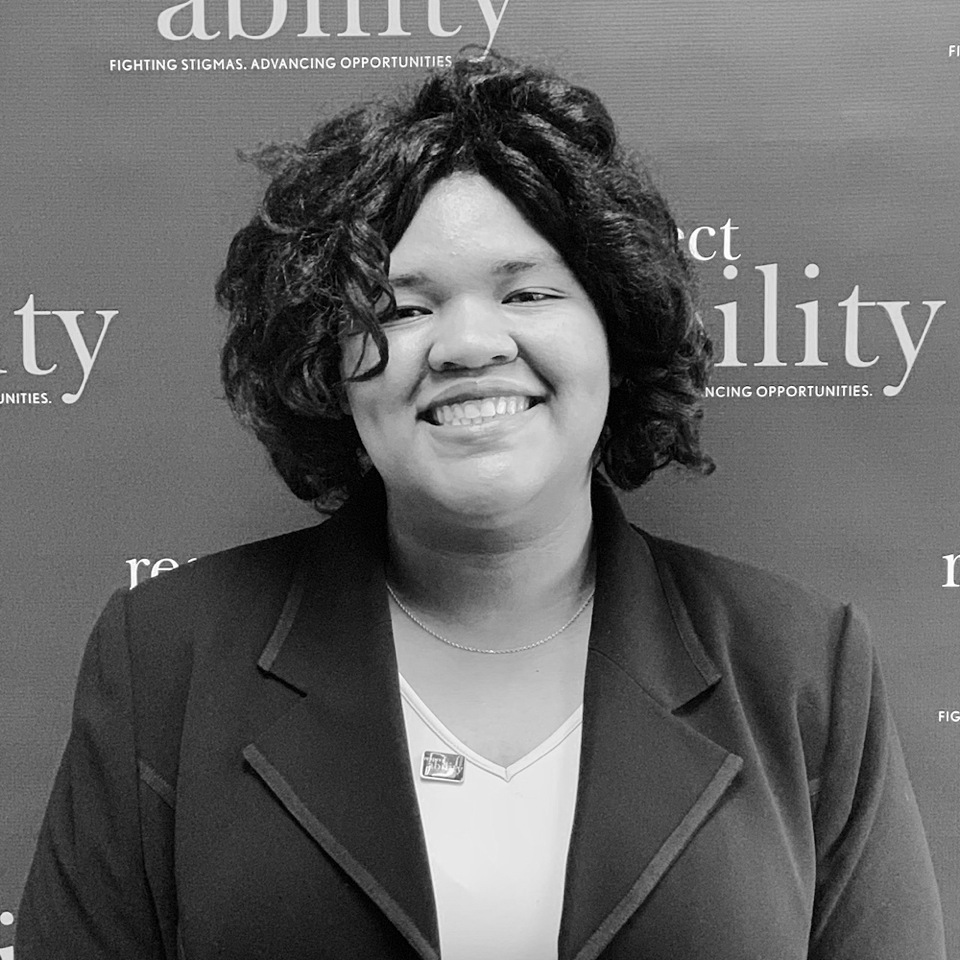 Angelica Vega smiling in front of the RespectAbility banner